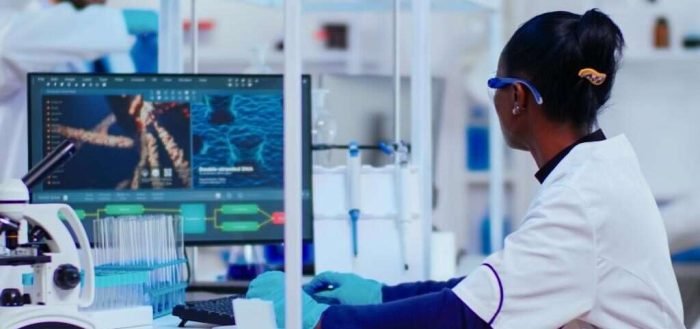 African woman biochemist researcher checking manifestations of vaccine working in modern equipped laboratory. Multiethnic doctors examining virus evolution using high tech researching diagnosis
