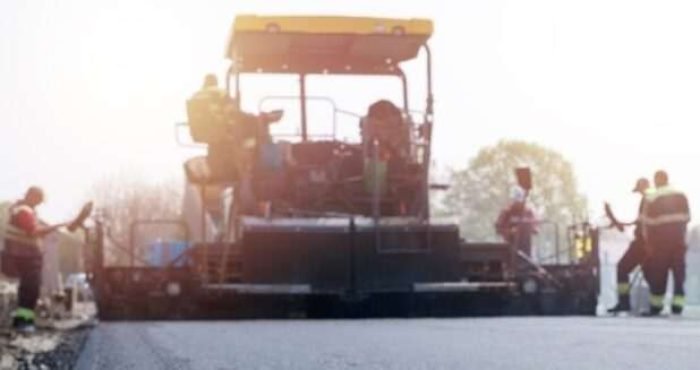 Workers placing new coating of asphalt on the road.